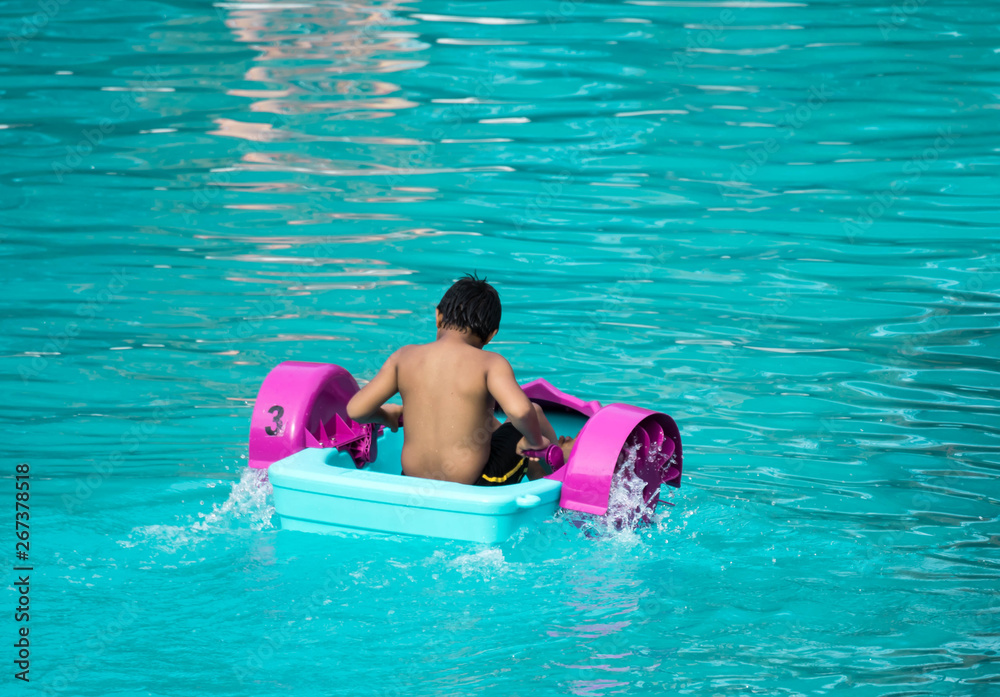 Child playing a water pedal boat in a swimming pool