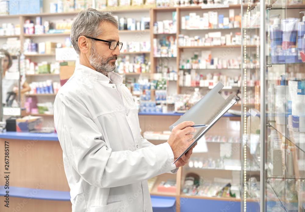 Man in lab coat working in pharmacy with medicaments.