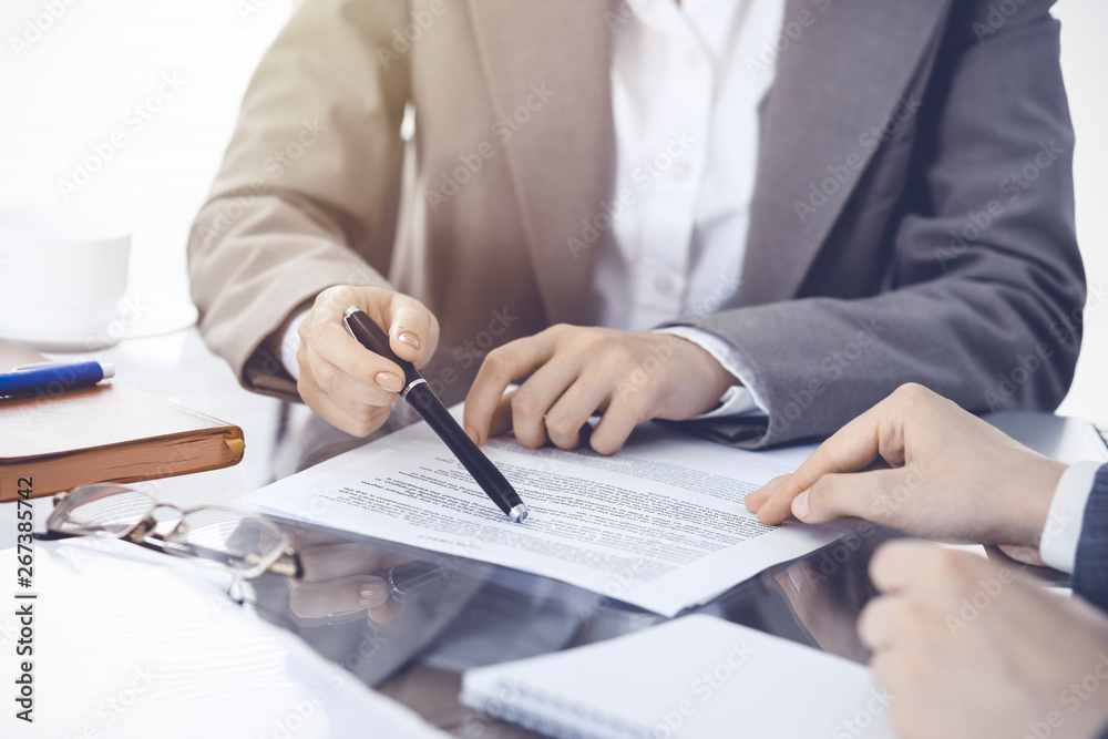 Group of business people or lawyers discussing contract papers sitting at the table, close-up Group of business people or lawyers discussing contract papers sitting at the table, close-up