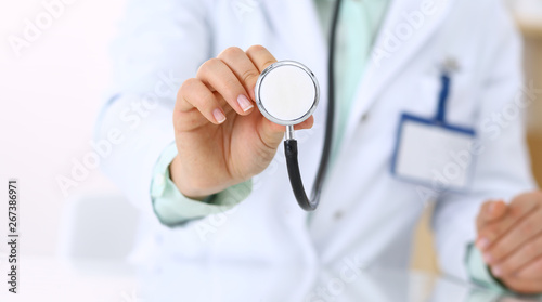 Unknown doctor holds stethoscope head, close-up. Medical help and insurance in health care, best treatment and medicine concept