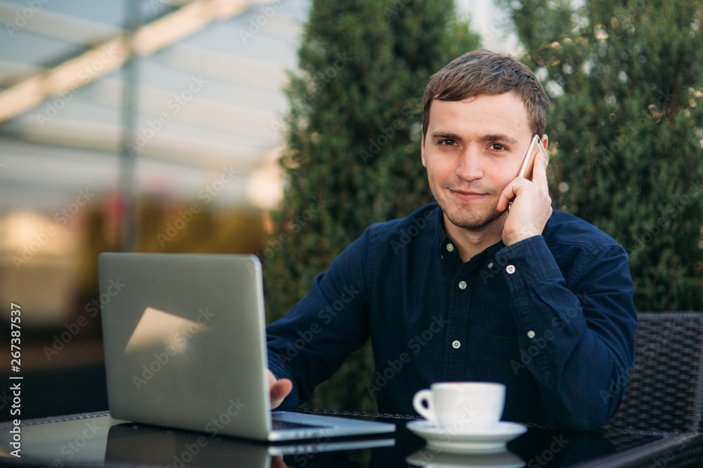 Young businessman call somebody and use laptop in cafe. Happy young man Young businessman call somebody and use laptop in cafe. Happy young man