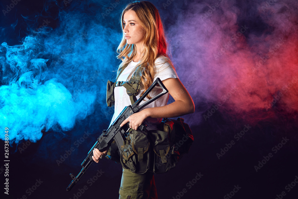 Woman in the army pros and cons. Women do not just serve, but attain high positions and ranks. Beautiful woman in military outfitholding weapon in hands stands in smoky background