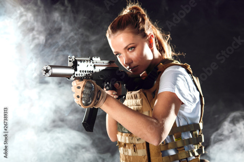 Obraz na plátne Portrait of a beautiful woman warrior in military outfit with firearm in hands,