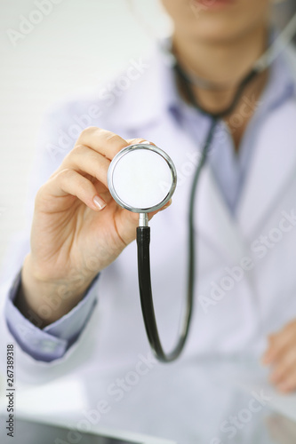 Doctor woman holds stethoscope head, close-up of hands. Physician ready to examine and help patient. Helping and insurance in health care, best treatment and medicine concept