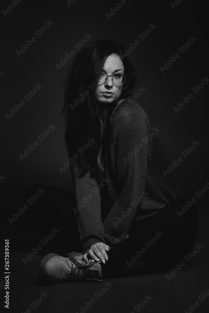 Wunderschönes schwarzhaariges Model in schwarzweiß im Studio mit Brille, Pullover und Stiefel Wunderschönes schwarzhaariges Model in schwarzweiß im Studio mit Brille, Pullover und Stiefel