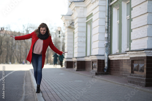 Pretty girl on a walk in red coat in the city