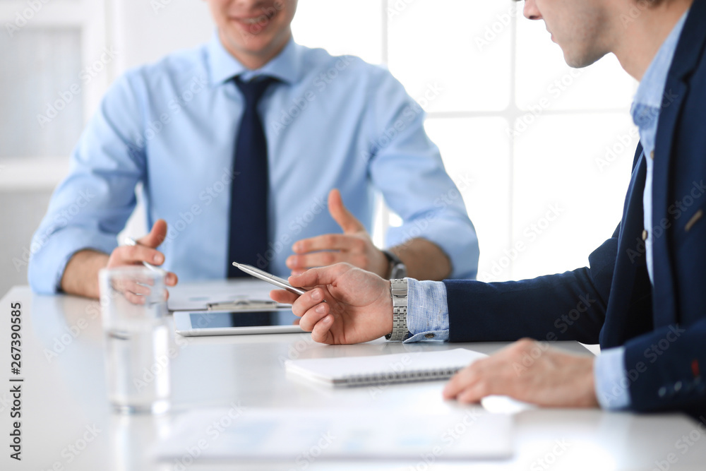 Group of unknown business people discussing questions at meeting in modern office, close-up of hands. Managers at negotiation or brainstorm. Teamwork, partnership and business concept Group of unknown business people discussing questions at meeting in modern office, close-up of hands. Managers at negotiation or brainstorm. Teamwork, partnership and business concept