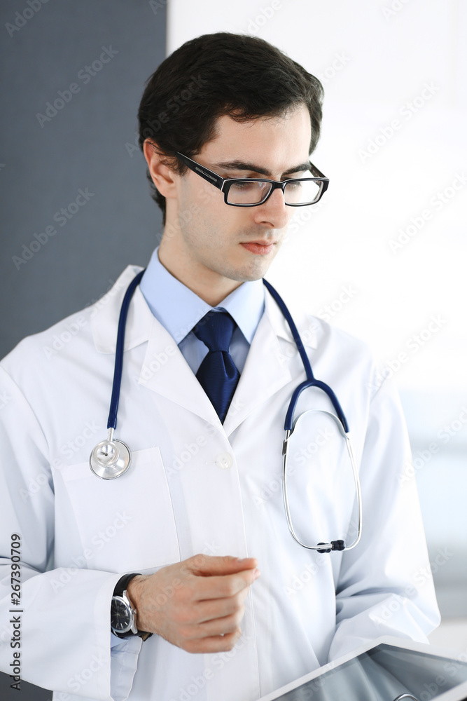 Doctor man using tablet computer for network research or virtual disease treatment. Perfect medical service in clinic. Modern medicine, medic data and healthcare concepts Doctor man using tablet computer for network research or virtual disease treatment. Perfect medical service in clinic. Modern medicine, medic data and healthcare concepts
