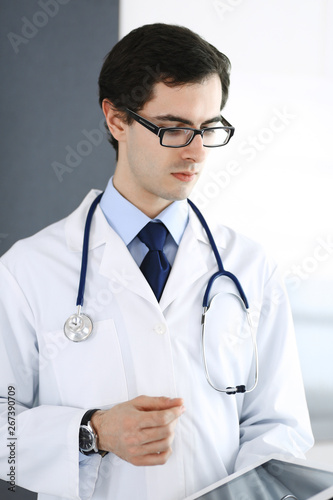 Doctor man using tablet computer for network research or virtual disease treatment. Perfect medical service in clinic. Modern medicine, medic data and healthcare concepts