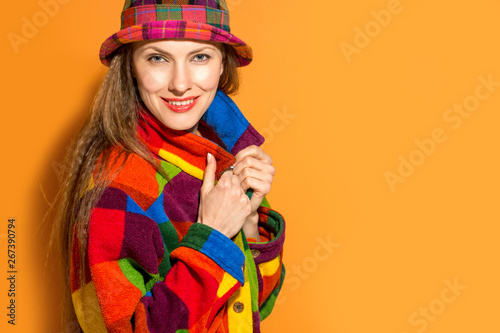 Autumn woman in hat and warm colorful clothes over bright orange background