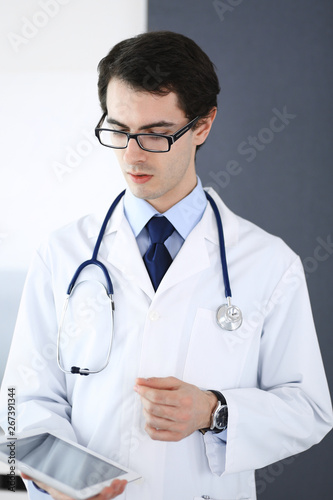 Doctor man using tablet computer for network research or virtual disease treatment. Perfect medical service in clinic. Modern medicine, medic data and healthcare concepts