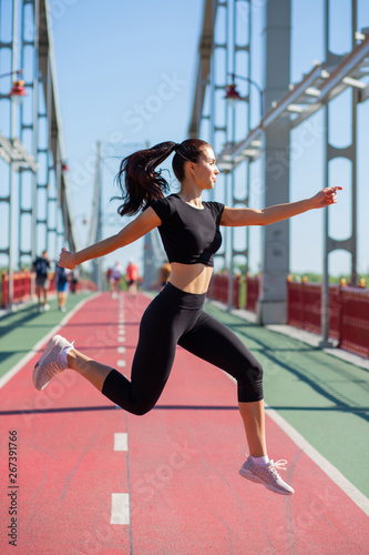 Sporty brunette girl jumping on the jogging track