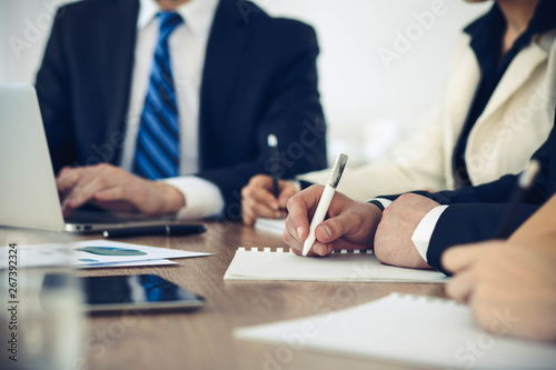 Group of business people or lawyers work together at meeting in office, hands using tablet and making notes close-up. Negotiation and communication concept