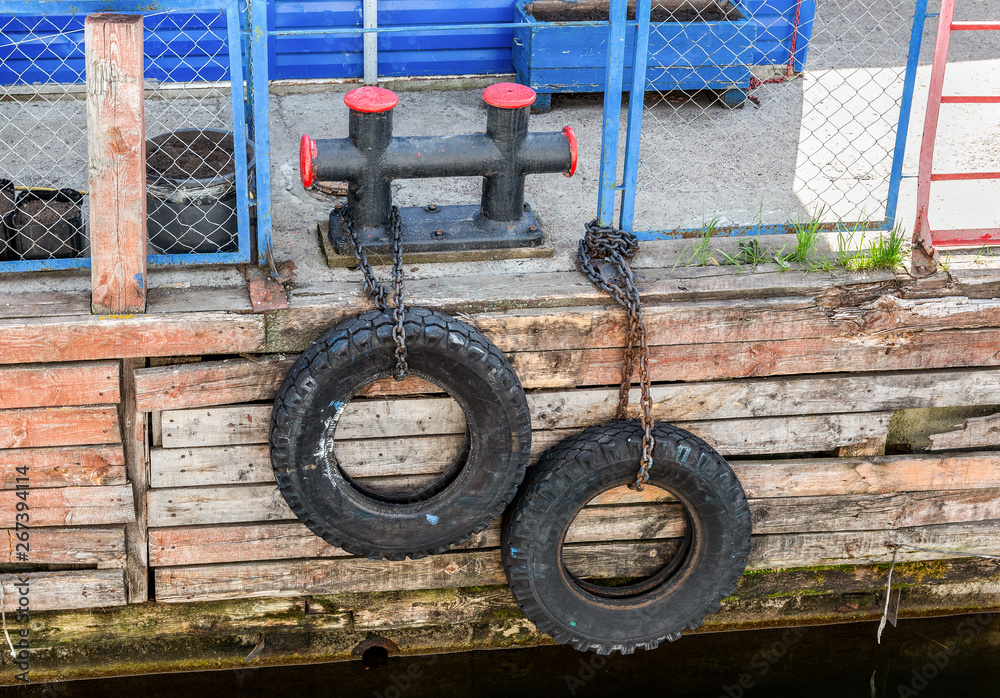 Fototapeta premium Mooring metal bollard with a tires at the pier