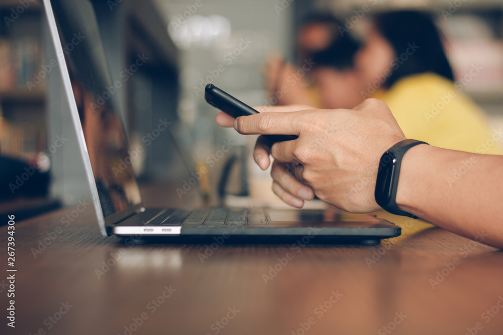 Businessman using laptop and typing on mobile smart phone, business people with technology concept. Close up hand man working at modern workplace using notebook computer and cell phone reading message
