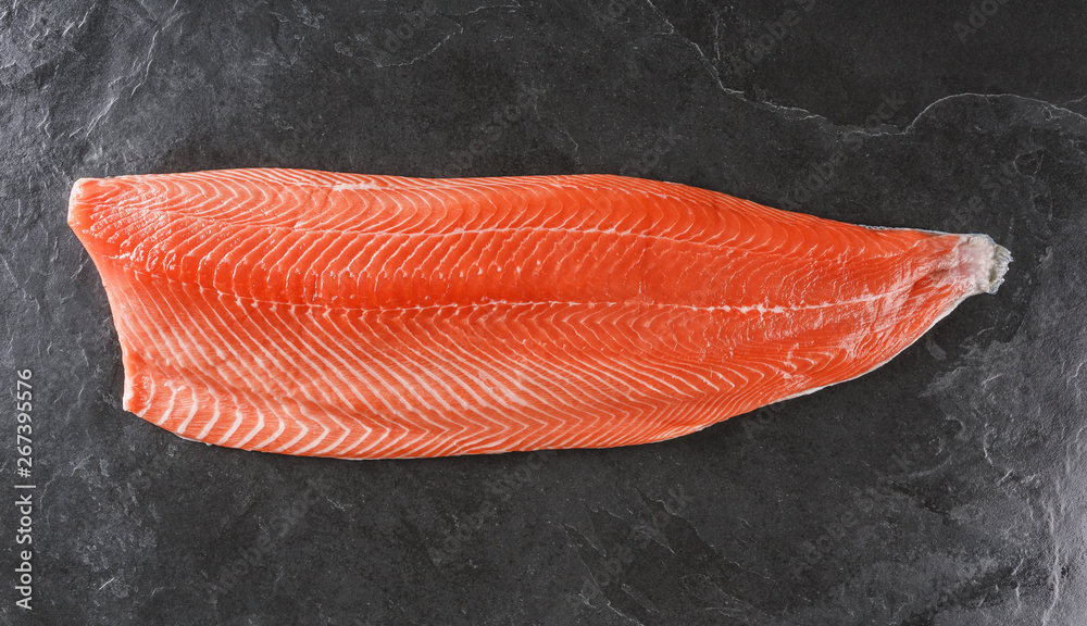 Fresh raw salmon fish steak with spices on ice over dark stone background. Creative layout made of fish, top view, flat lay Fresh raw salmon fish steak with spices on ice over dark stone background. Creative layout made of fish, top view, flat lay