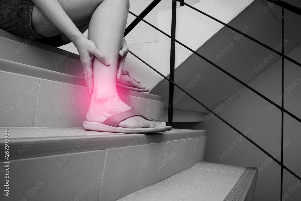 Woman has calf cramp and touching hurt leg during go down stairs. Black