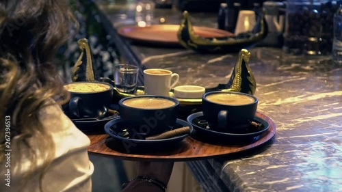 Waitress is carrying tray to serve turkish coffee, chocolate and salep.