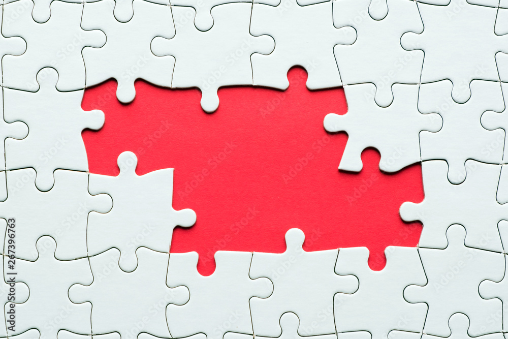 White jigsaw puzzle game pieces on red background form a banner for business theme design White jigsaw puzzle game pieces on red background form a banner for business theme design