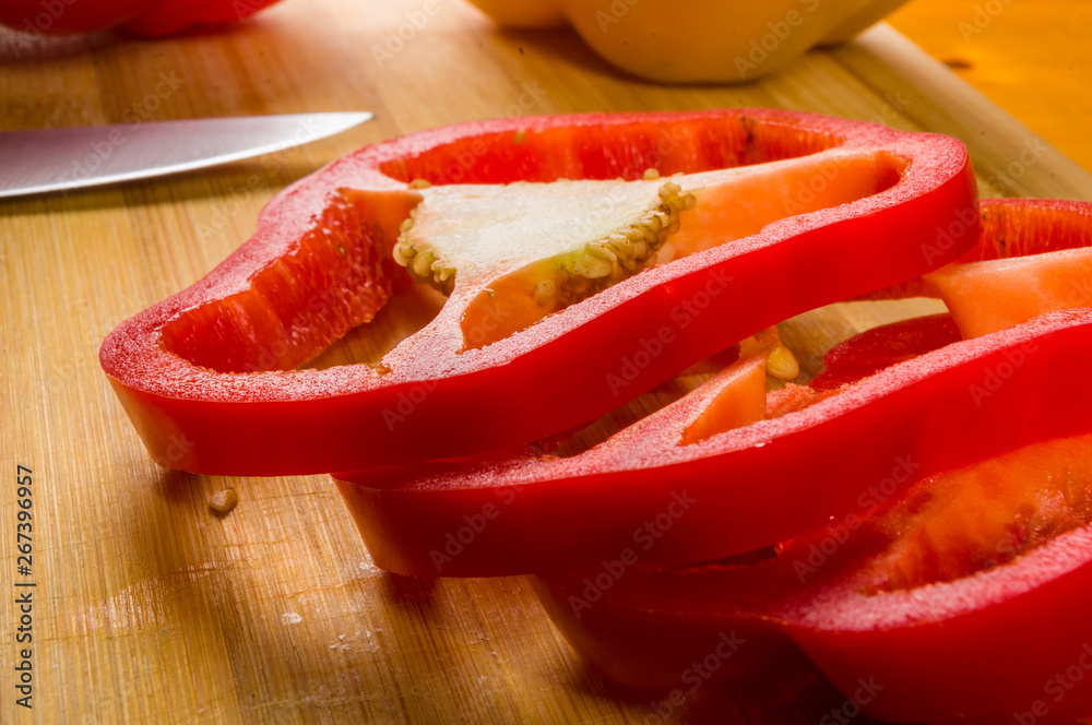 sliced fresh red paprika, bell pepper on bamboo cutting board sliced fresh red paprika, bell pepper on bamboo cutting board