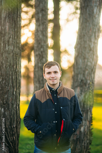 Young man in dark blue shirt posing for photographer in the park