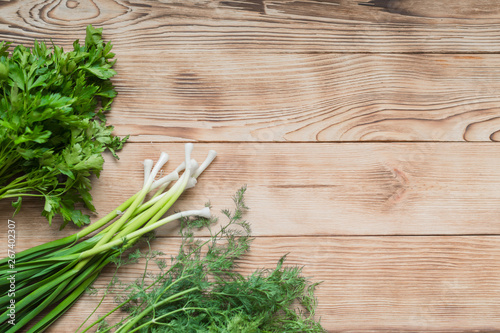 Fresh organic herbs: parsley, dill and onion on a wooden background.
