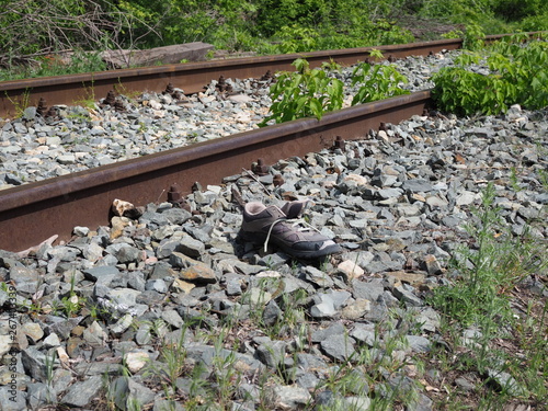 one lost male sneaker lies near the rails on the railway