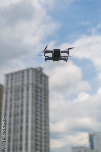 Flying drone against the sky with clouds and buildings.