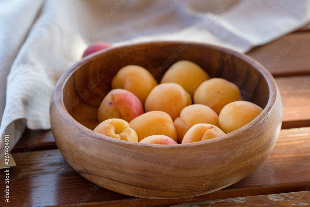 The ripe apricots, juicy fresh yellow with red outflow, which grew on the Azerbaijani earth in a wooden cup in beams of the sunset sun. Macro.
