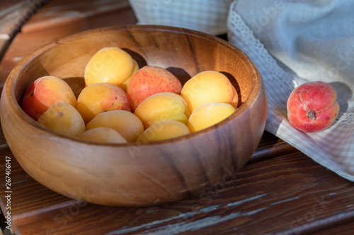 The ripe apricots, juicy fresh yellow with red outflow, which grew on the Azerbaijani earth in a wooden cup in beams of the sunset sun. Macro.