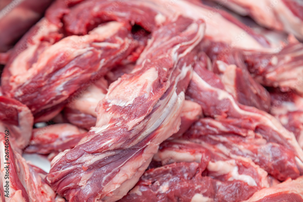 Closeup cutting fillet of fresh pieces of pork and beef meat on plastic cutting board in restaurant kitchen. Concept carve meat for grill barbeque on farmer local market