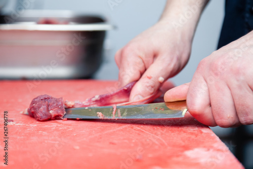 Closeup male hands cut raw pork on plastic board in restaurant kitchen, process of cooking meat for barbeque. Concept carve meat for grill barbeque on farmer local market