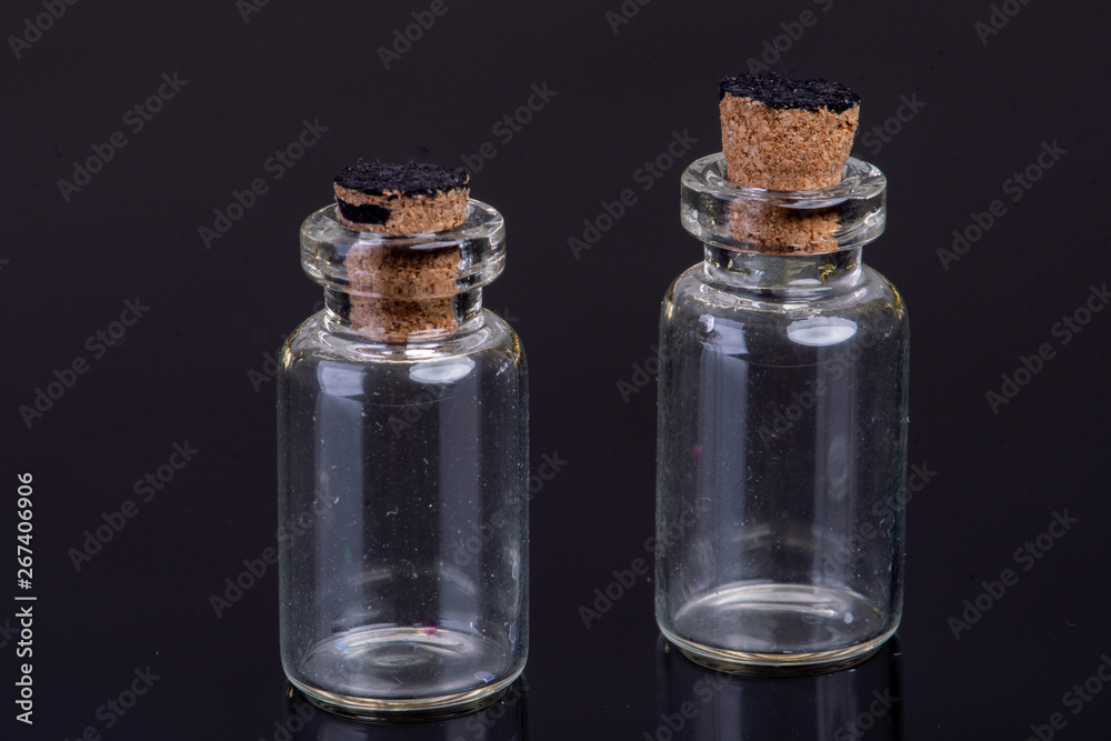 empty small glass bottles with a cork closure on a black background