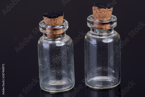 empty small glass bottles with a cork closure on a black background with text space