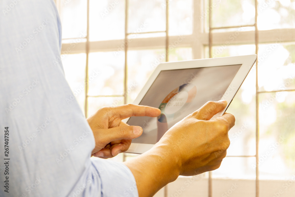 Business man working on the Tablet with 2020 goals stock market chart.