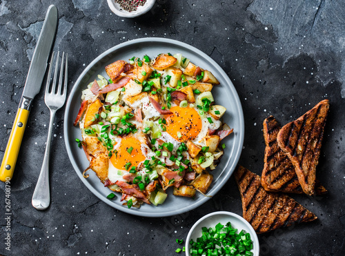 Potatoes, ham, eggs breakfast hash on a dark background, top view. Delicious, nutritious breakfast, snack