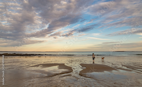 Woman with her dog walks on the beach in Maine USA photo