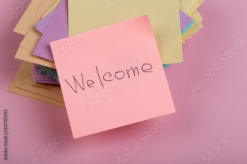greeting concept - The text "Welcome" written by hand on sticker on pink background