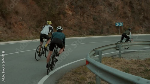 Group of road cyclists or three teammates cruise down empty sunset road during training or weekend ride. Slow motion epic and cinematic shot of athletic young people excercising in free time