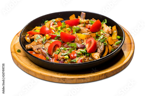 roast meat with potatoes decorated with fresh vegetables in a cast iron pan