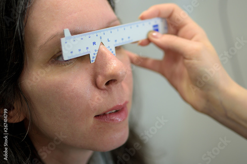 ophthalmologist optometrist optician making eyes measurements for a pretty young woman patient, low depth of field
