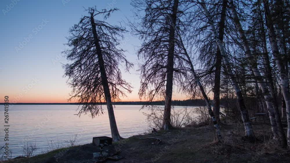 Time-lapse video of sunset, blue hour and stars reflecting in a northern lake with pine trees along the shoreline Time-lapse video of sunset, blue hour and stars reflecting in a northern lake with pine trees along the shoreline