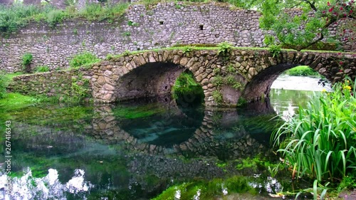 medieval stone bridge in eden colourful garden vibrant with roses and river