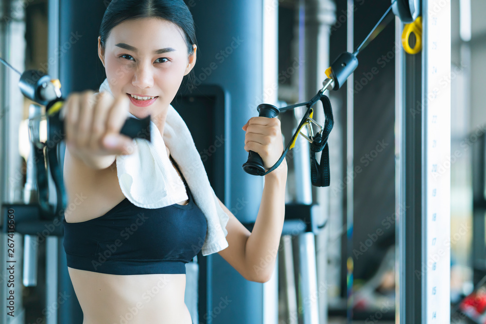 Fototapeta premium beautiful asian sport woman workout with weight machine to exercise in fitness beautiful woman lifts heavy dumbbell while training in the fitness Sports concept bodu builder healthy lifestyle