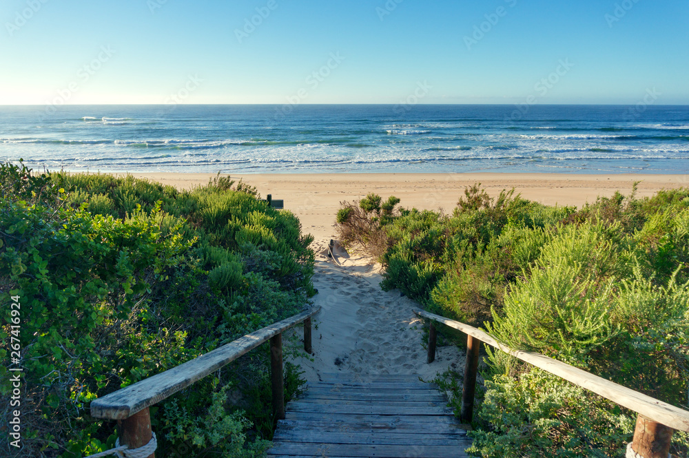 Ocean view beach background with wooden path covered in sand