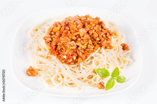 Spaghetti bolognese on a plate decorated with fresh basil in a white background