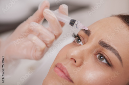 Close up cropped shot of a beautiful woman getting anti aging wrinkles treatment at beauty clinic. Professional cosmetologist doing hyaluronic acid injections in the face of female patient