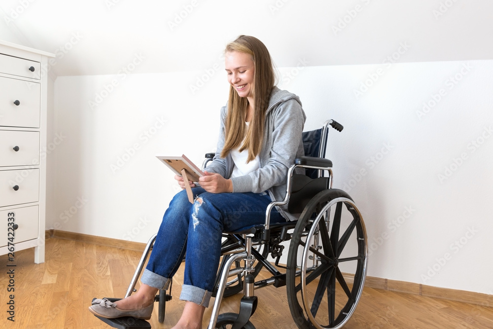 Disabled woman is looking at the photo in frame and smiling. Disabled woman is looking at the photo in frame and smiling.