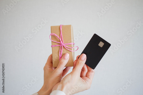 Woman holding a box with a gift, showing business card to the camera, front view, close up, background with copy space, for advertising or slogan