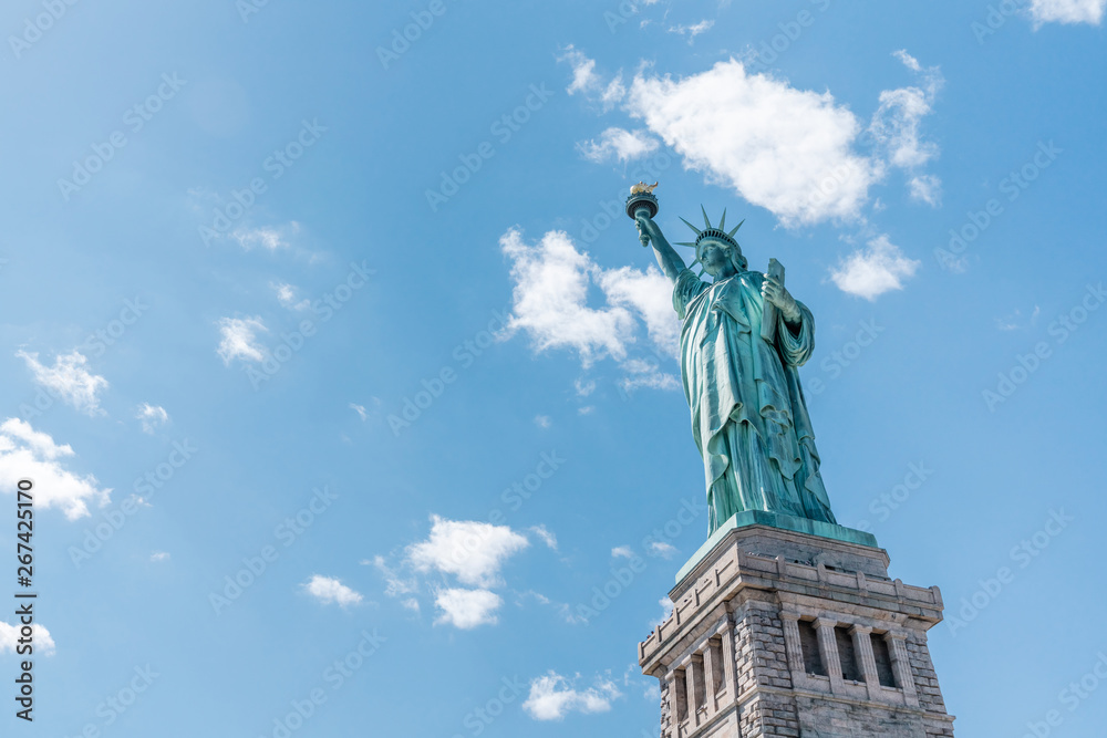 Obraz premium Statue of Liberty on sunny day, clear blue sky background. United States nation symbol, travel destination or America tourist attraction concept